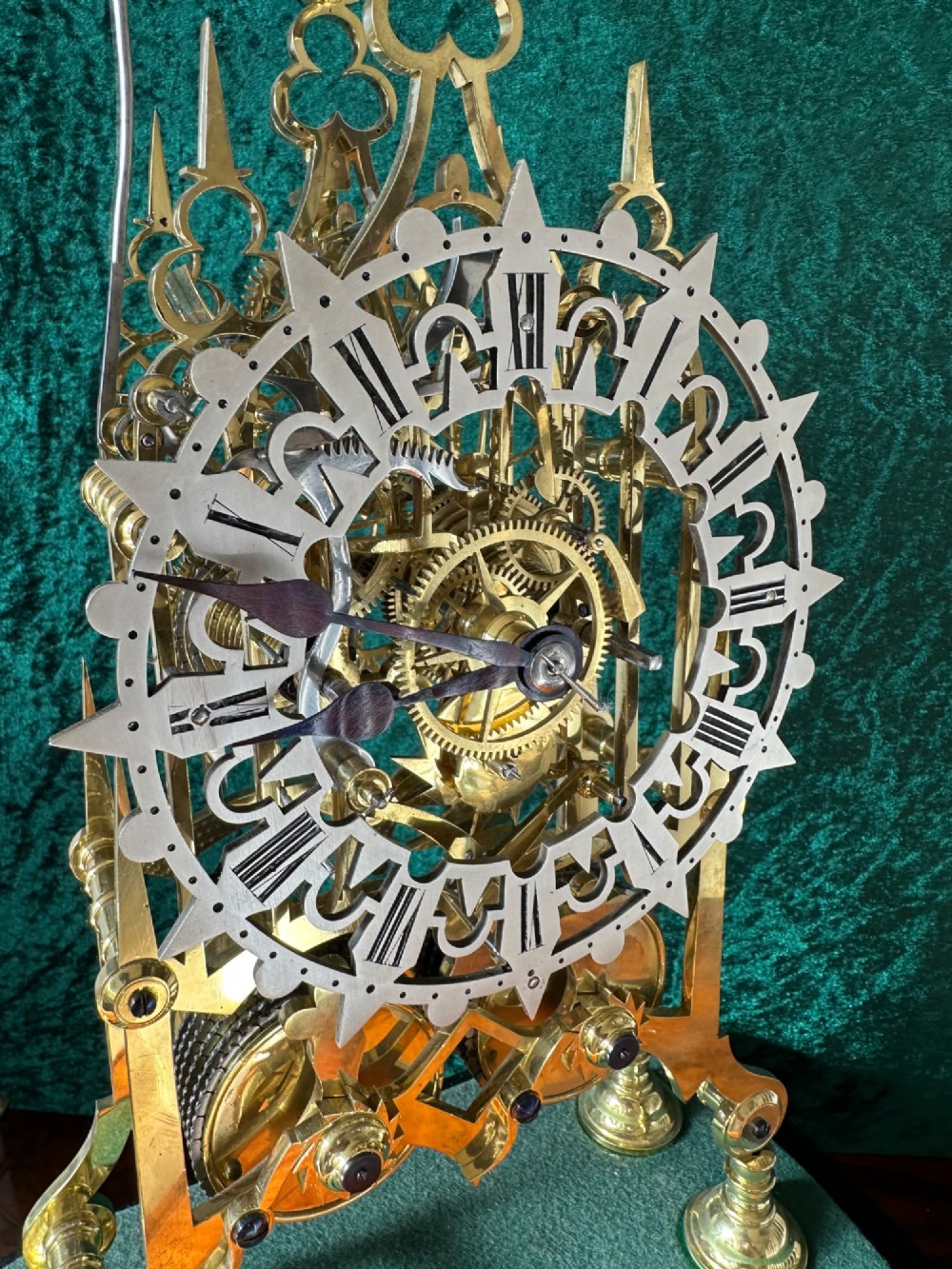 A Victorian brass double fusee skeleton clock displaying exposed internal gearing, a gothic pierced frame, a silvered chapter ring, and a top-mounted bell. View V