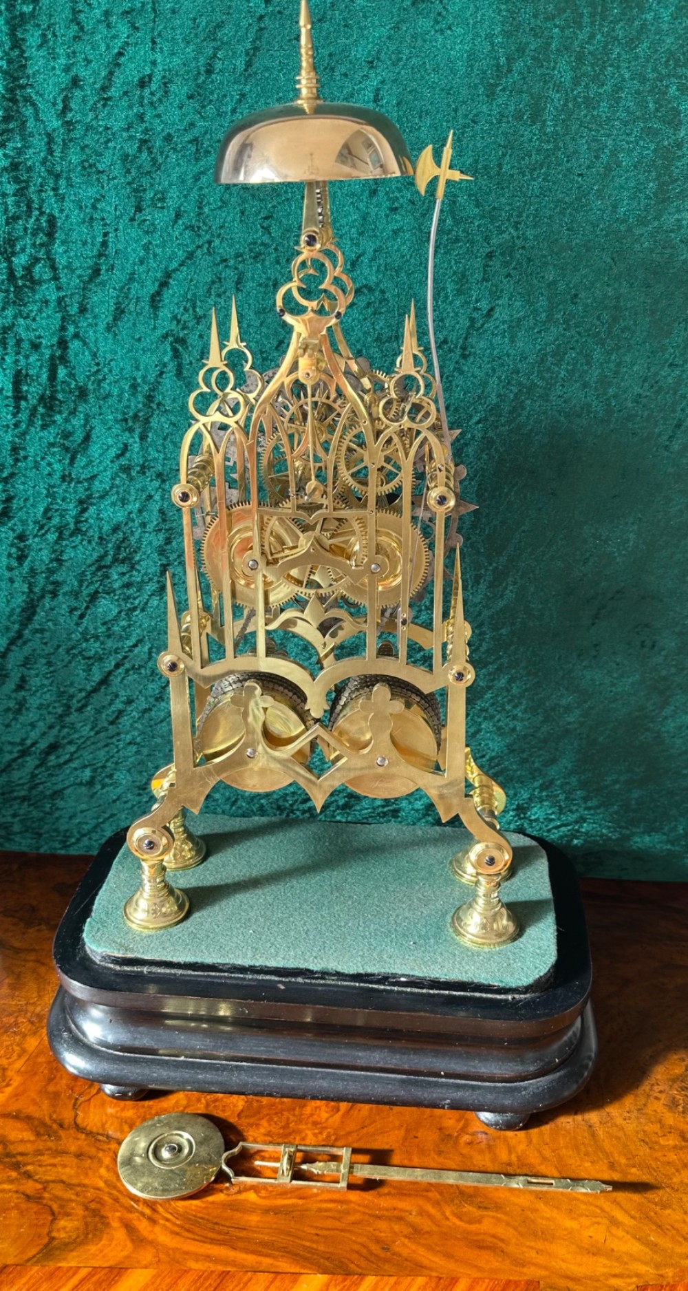 A Victorian brass double fusee skeleton clock displaying exposed internal gearing, a gothic pierced frame, a silvered chapter ring, and a top-mounted bell. View VI