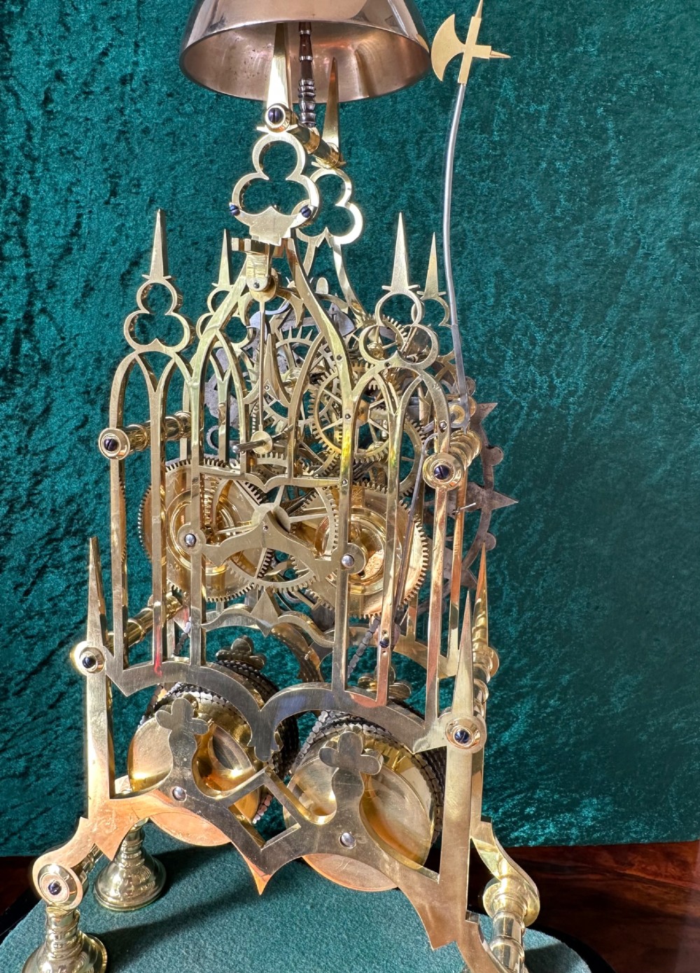 A Victorian brass double fusee skeleton clock displaying exposed internal gearing, a gothic pierced frame, a silvered chapter ring, and a top-mounted bell. View XIII