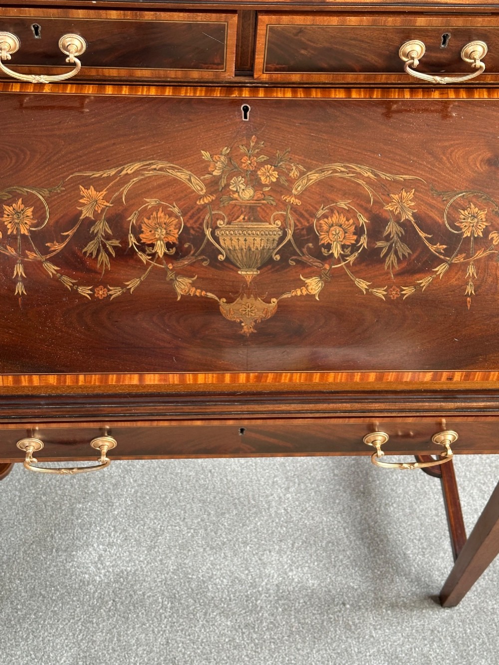 An Edwardian mahogany cylinder bureau featuring floral marquetry inlay on the curved front, brass handles, square tapered legs, and crossbanded borders. View II