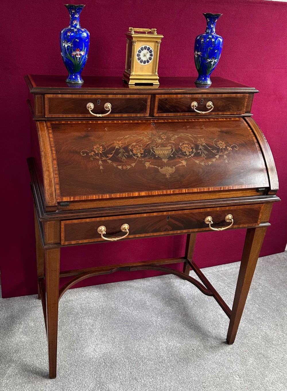An Edwardian mahogany cylinder bureau featuring floral marquetry inlay on the curved front, brass handles, square tapered legs, and crossbanded borders. View VIII