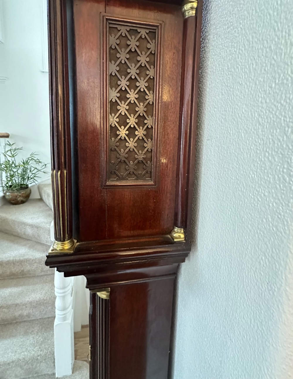 A tall Georgian mahogany longcase clock featuring brass eagle finials, a swan-neck pediment, fluted columns, and an engraved brass dial. View V