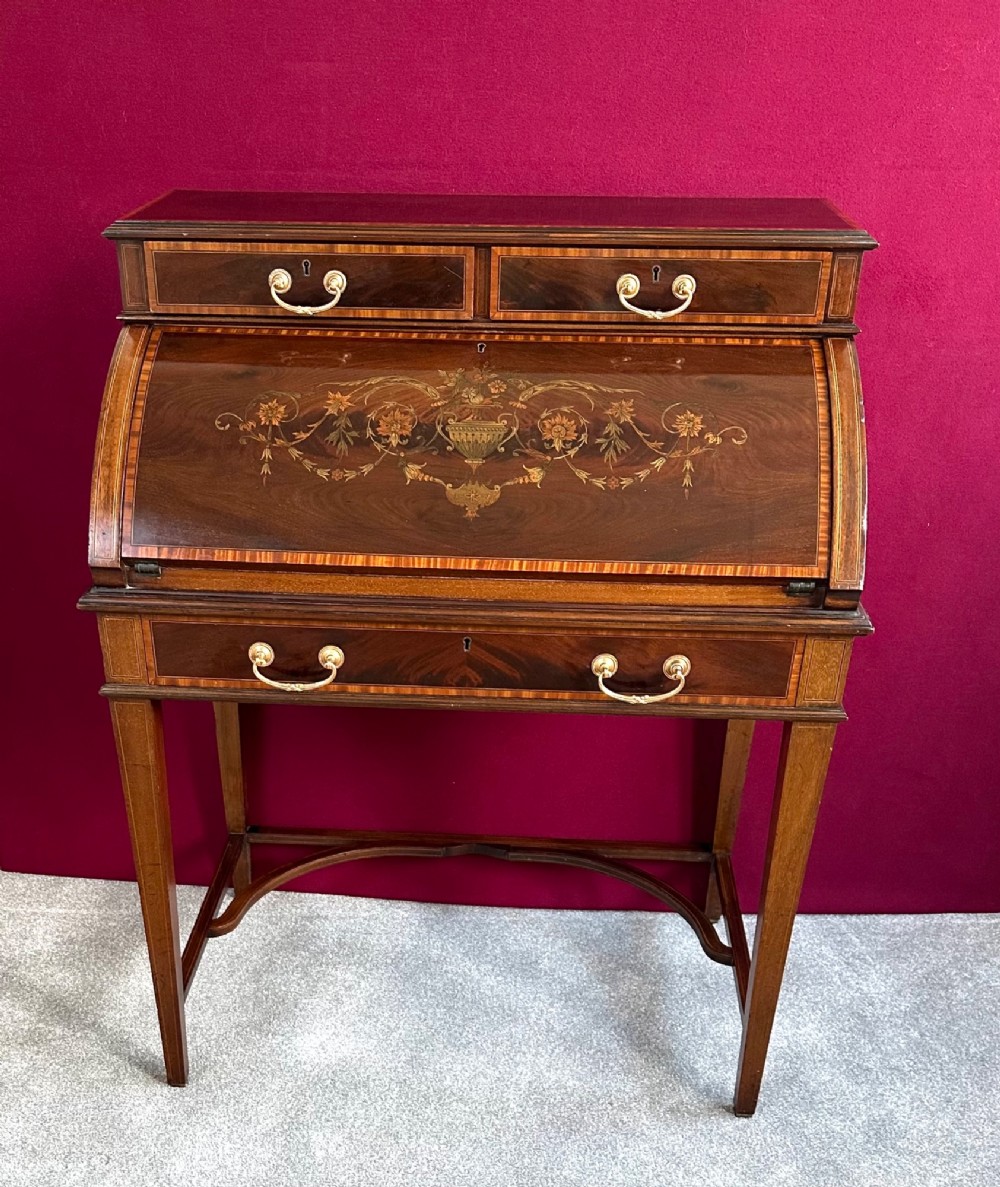 An Edwardian mahogany cylinder bureau featuring floral marquetry inlay on the curved front, brass handles, square tapered legs, and crossbanded borders. View XIII