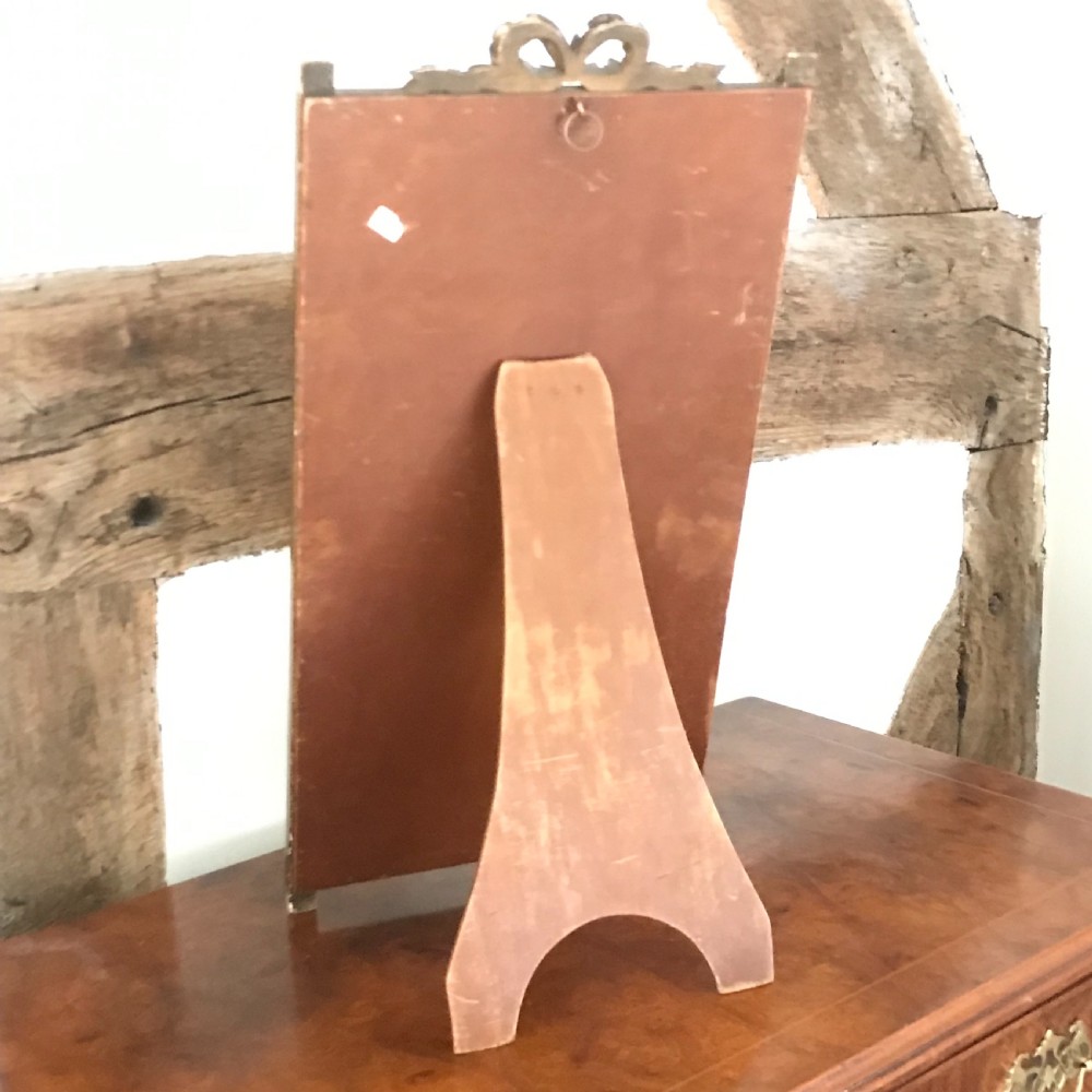 A rectangular French gilded easel mirror featuring a carved twist border, a top panel depicting a period scene, and mirror glass below. View VII