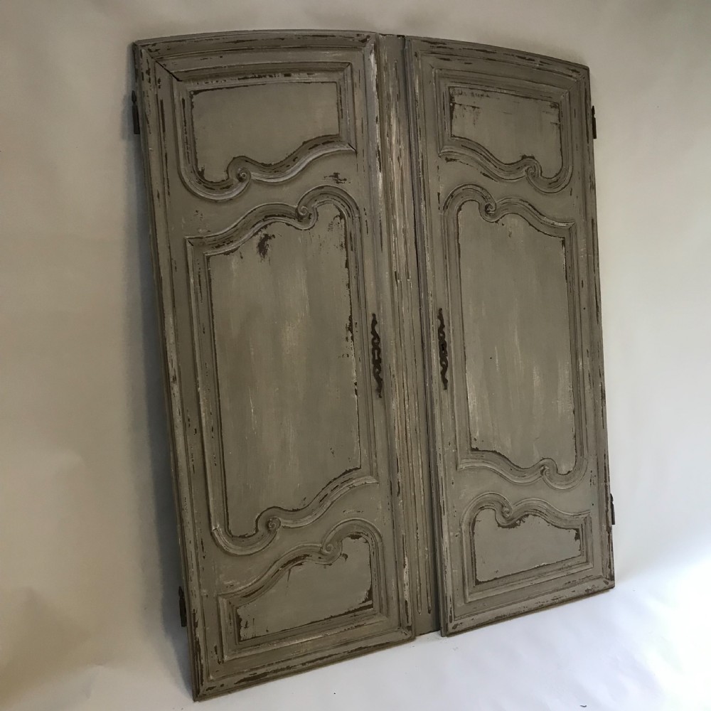 A pair of grey painted wooden doors featuring carved Louis XV style moulded panels and a distressed paint finish with central iron escutcheons. View III
