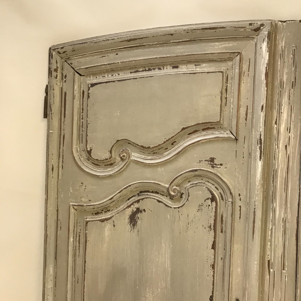 A pair of grey painted wooden doors featuring carved Louis XV style moulded panels and a distressed paint finish with central iron escutcheons. View V