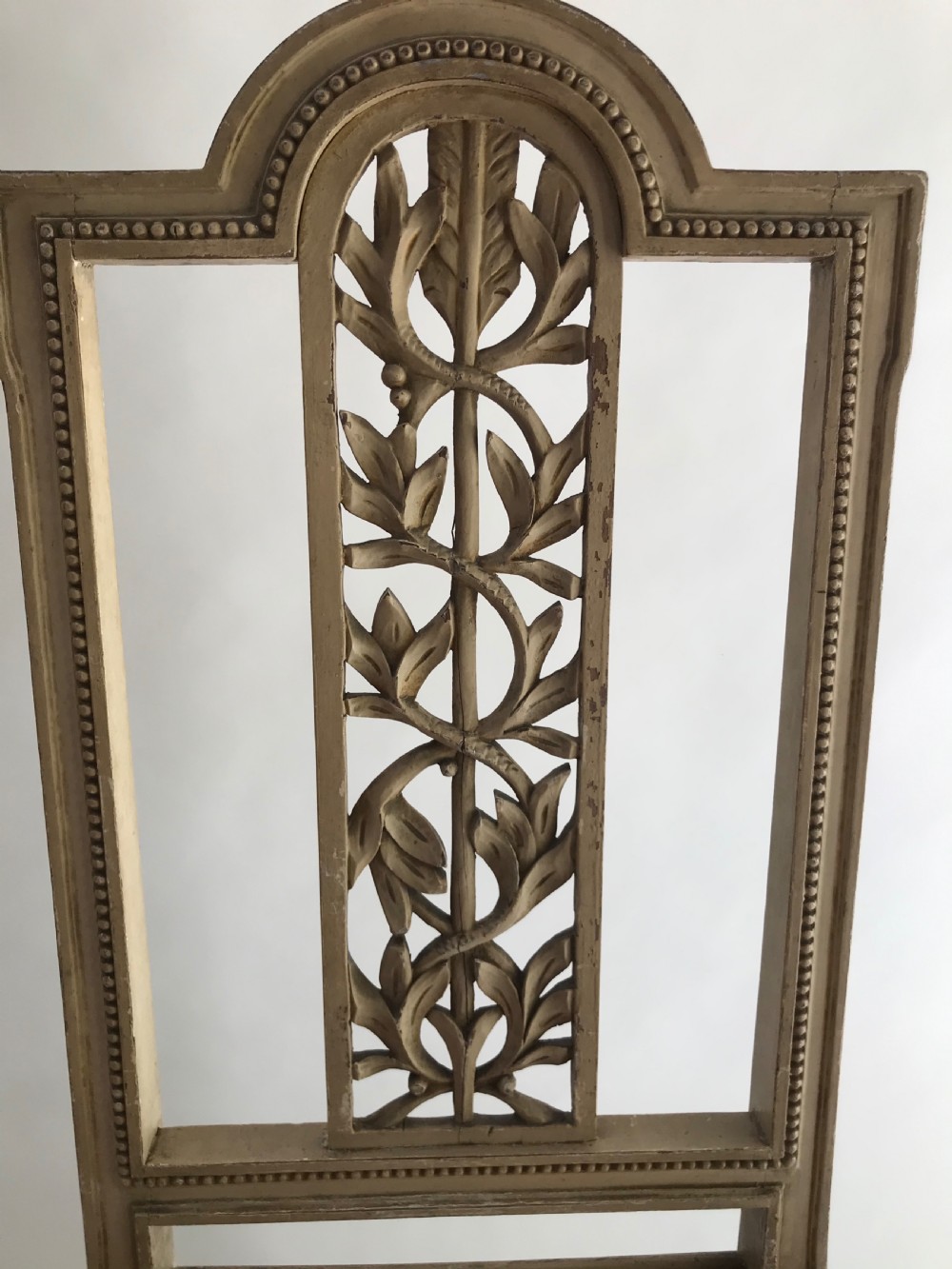 A pair of French painted timber side chairs featuring foliate back carving, woven cane seats, and spiral-turned front legs. View III