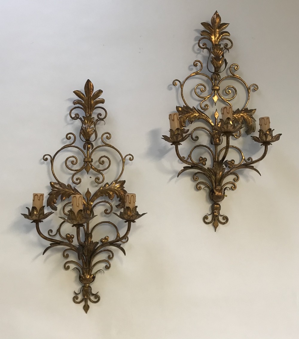 A pair of large French gilt metal three-light wall sconces with elaborate scrollwork and acanthus leaf details.