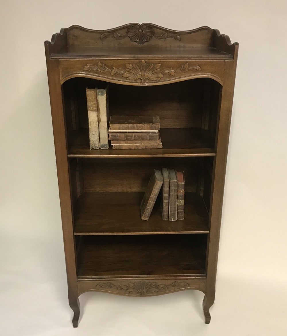 A hand-carved French walnut open bookcase featuring three shelves, carved floral cresting, panelled sides, and cabriole legs. View II