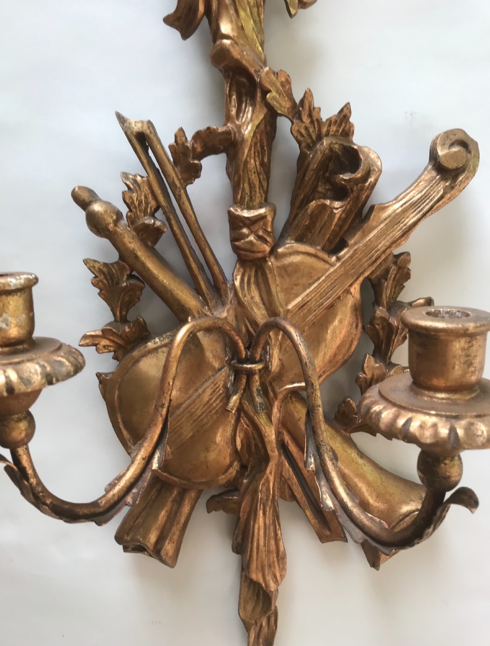 A pair of gold giltwood wall sconces carved with ribbon crests, violins, horns, and two candle branches each. View II