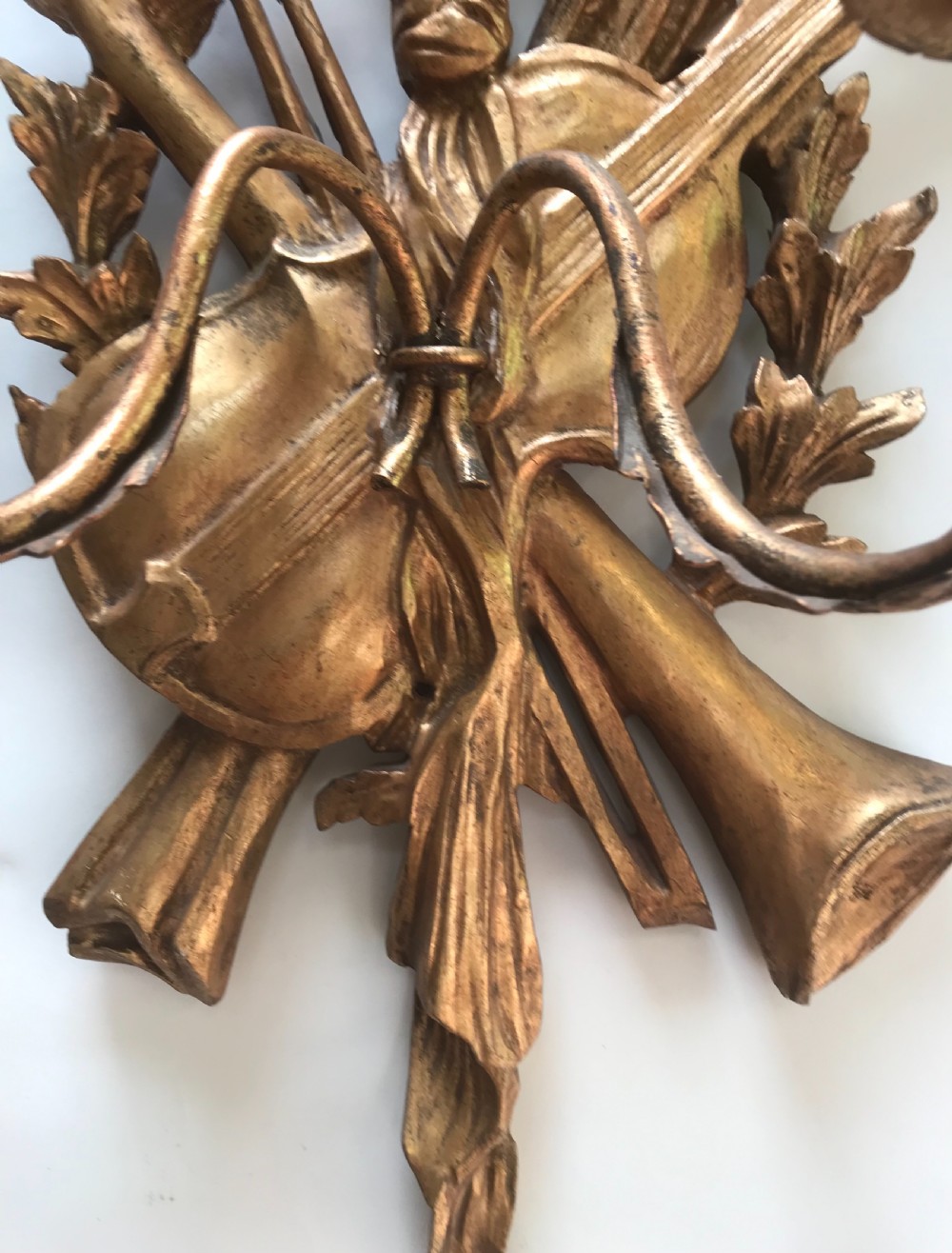 A pair of gold giltwood wall sconces carved with ribbon crests, violins, horns, and two candle branches each. View V