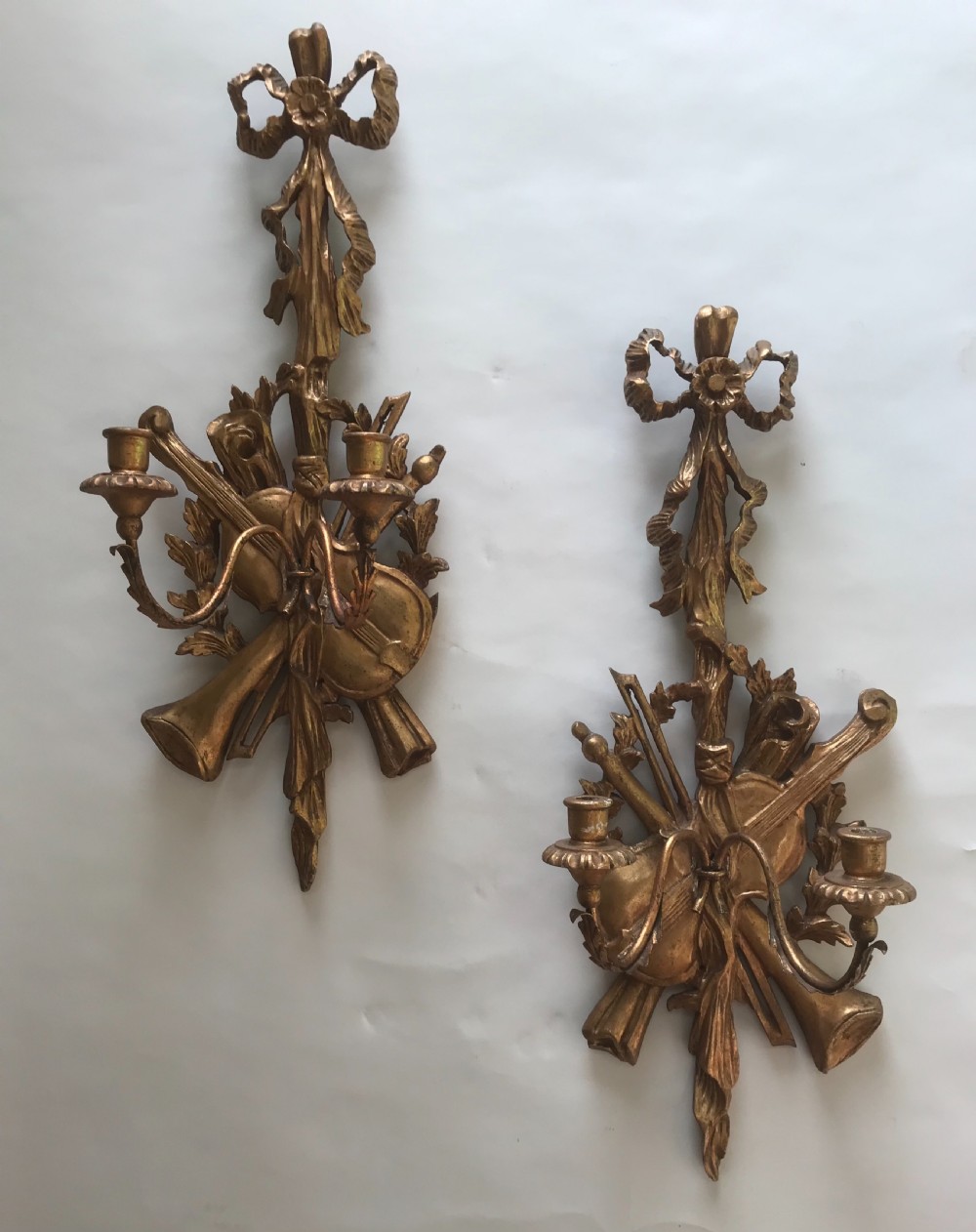 A pair of gold giltwood wall sconces carved with ribbon crests, violins, horns, and two candle branches each. View VII