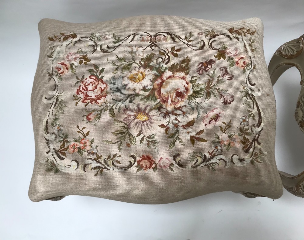 A pair of French Louis XV style footstools with painted cabriole legs, gilded accents, and floral needlepoint upholstery. View III