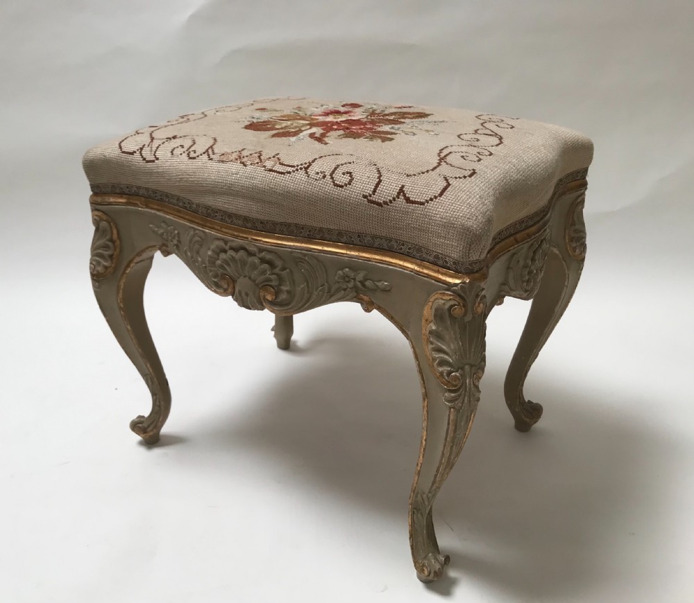 A pair of French Louis XV style footstools with painted cabriole legs, gilded accents, and floral needlepoint upholstery. View IV