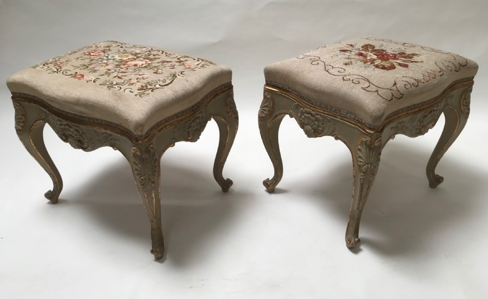 A pair of French Louis XV style footstools with painted cabriole legs, gilded accents, and floral needlepoint upholstery. View VII
