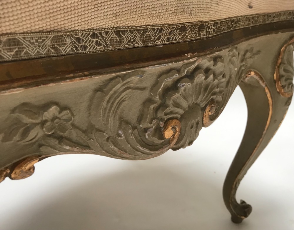 A pair of French Louis XV style footstools with painted cabriole legs, gilded accents, and floral needlepoint upholstery. View VIII