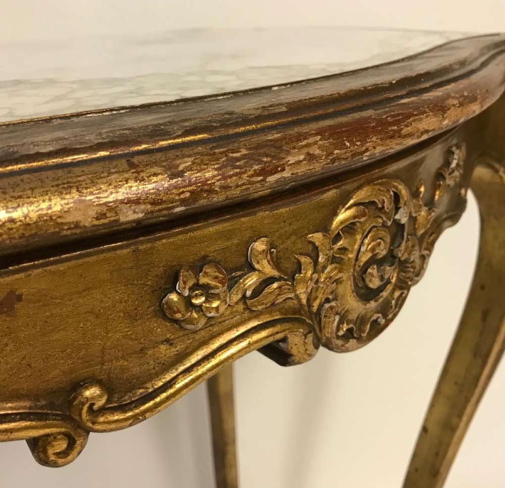 A French Louis XV style giltwood side table featuring a contoured white marble top, carved cabriole legs, and an X-shaped stretcher with a central shell motif. View II