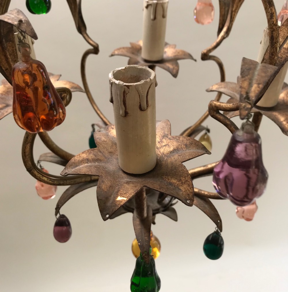 An Italian ceiling chandelier with a gilded wrought-iron frame forming leaf motifs and hanging colourful glass fruit drops. View II