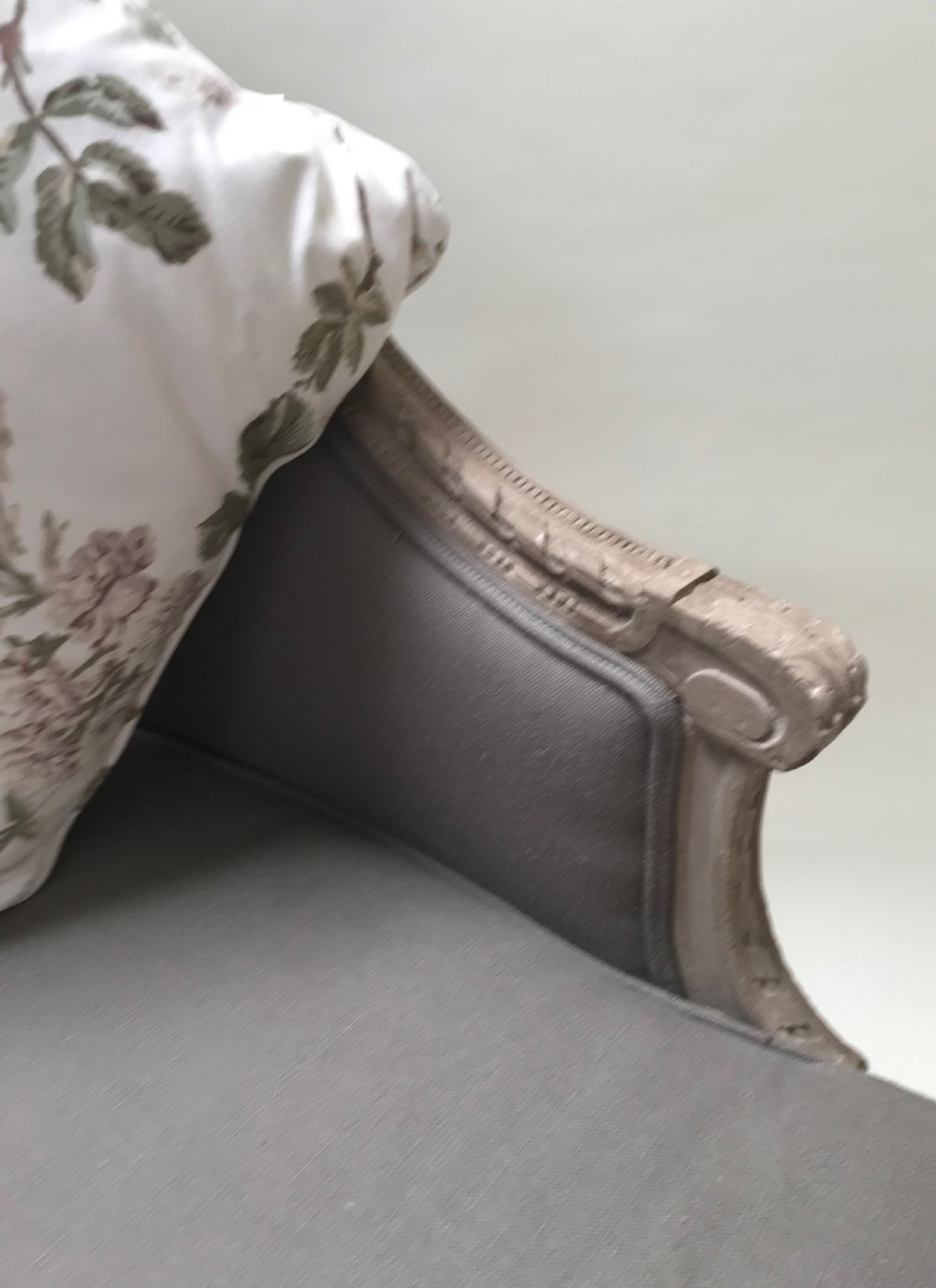A French Louis XVI style upholstered daybed featuring a carved taupe-grey timber frame, fluted legs, a grey cushion seat, and a floral accent pillow. View III