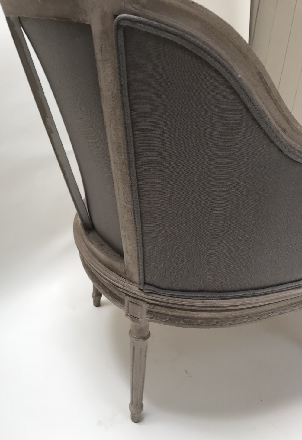 A French Louis XVI style upholstered daybed featuring a carved taupe-grey timber frame, fluted legs, a grey cushion seat, and a floral accent pillow. View VII