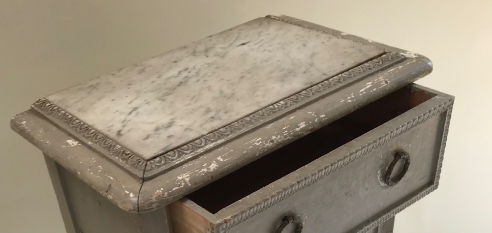 A tall, narrow French grey painted chest of three drawers featuring ring pulls, detailed trim moulding, turned legs, and an inset marble top. View III