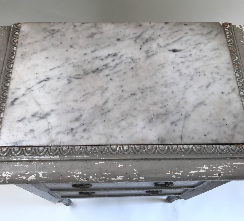 A tall, narrow French grey painted chest of three drawers featuring ring pulls, detailed trim moulding, turned legs, and an inset marble top. View V