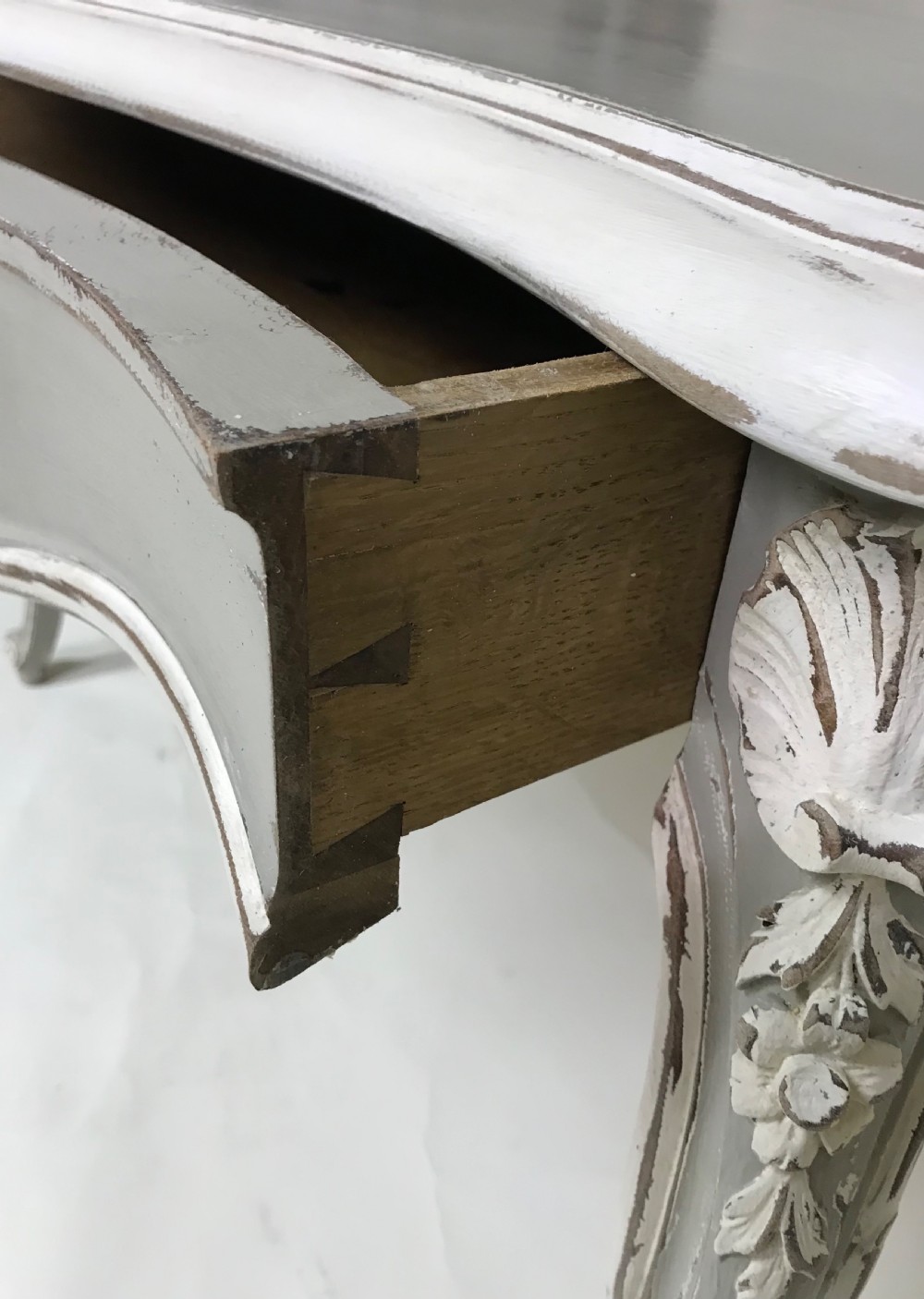 A grey painted French Rococo style side table featuring carved white foliate accents and slender cabriole legs. View VII