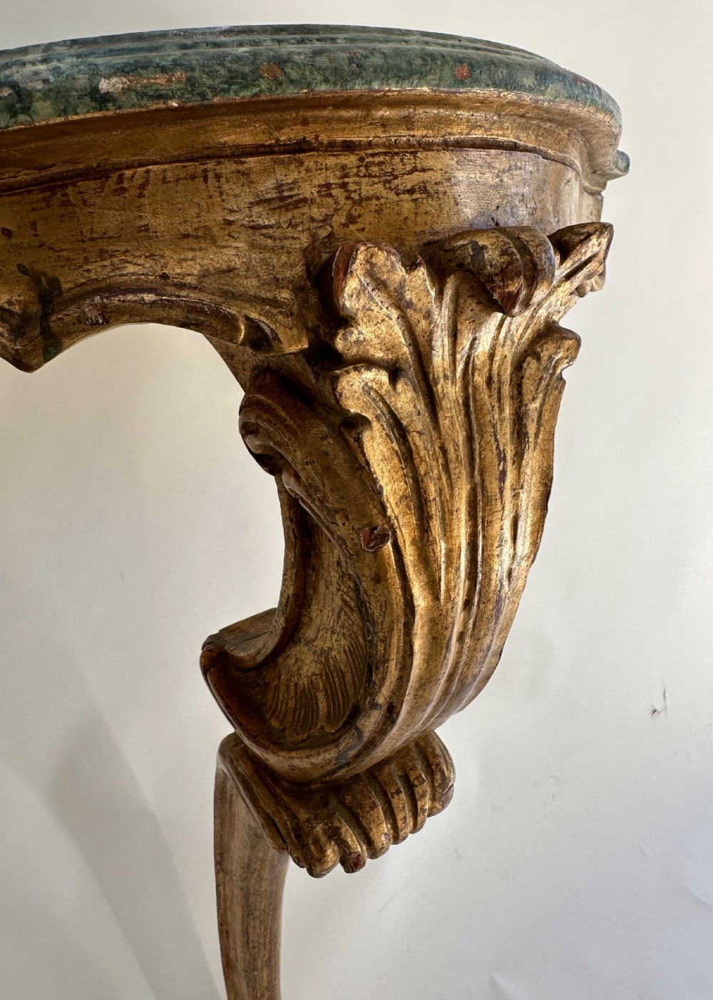 A wall-mounted Italian gilded console table featuring a single curved carved leg and a dark green marble top. View II
