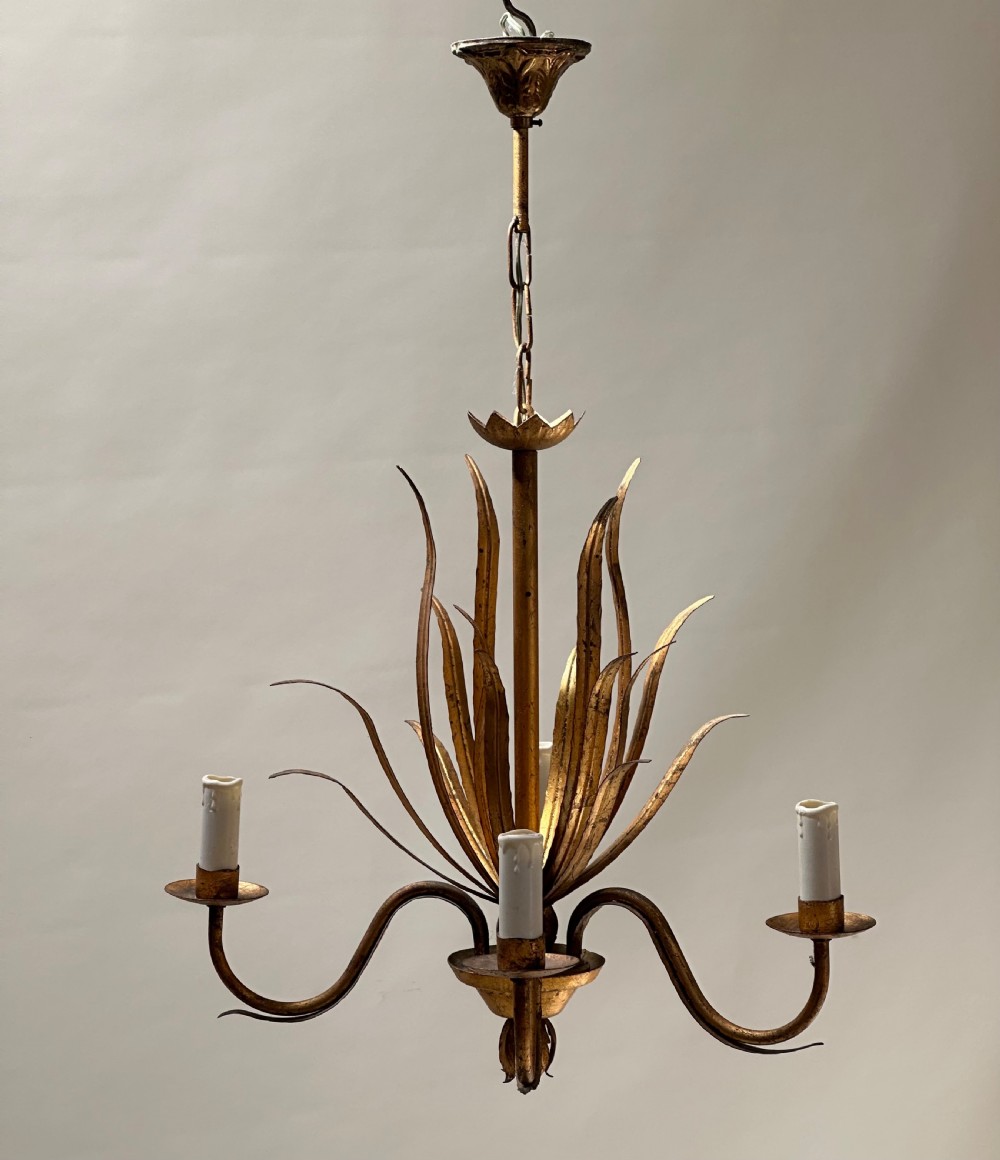A French gilded metal chandelier featuring central vertical foliage leaves and three curved candle arms.