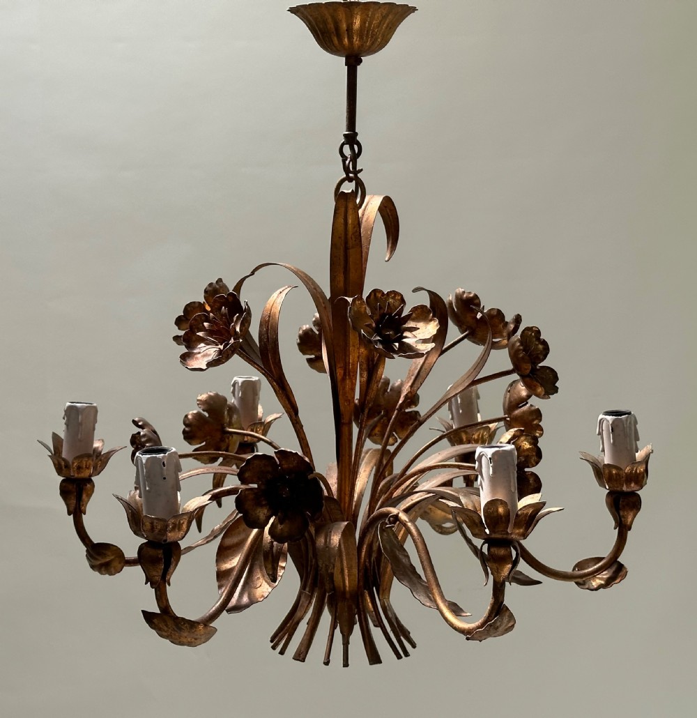 A French gilt metal multi-arm ceiling chandelier featuring sculptured flower petals, leaf motifs, and six candle-style light sockets.