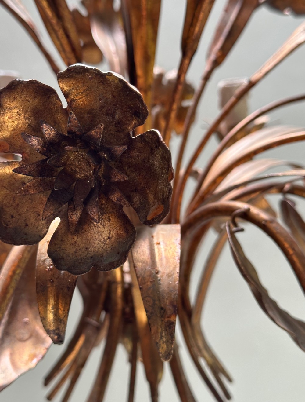A French gilt metal multi-arm ceiling chandelier featuring sculptured flower petals, leaf motifs, and six candle-style light sockets. View II