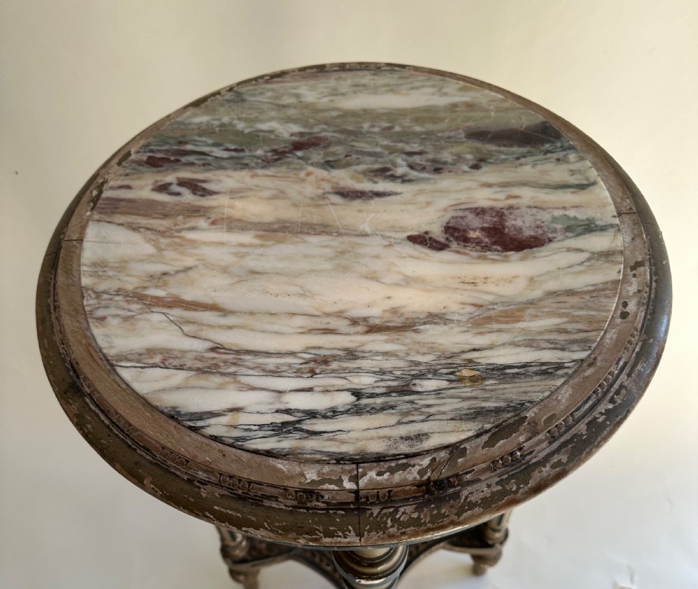 A circular French Louis XVI style occasional table featuring a veined marble top, distressed grey paint with gilt details, fluted legs, and a low X-frame stretcher. View III