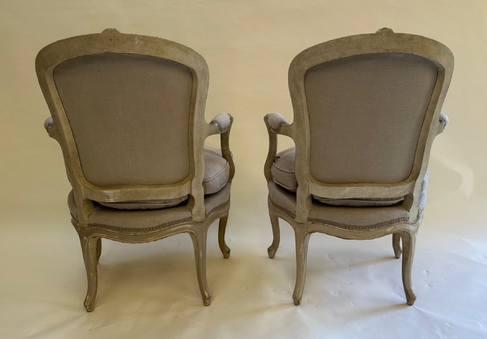 A pair of French Louis XV style open armchairs with grey painted carved wooden frames and neutral linen upholstery. View III