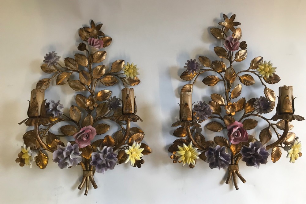 A pair of French gilt metal wall sconces shaped as botanical floral bouquets with colourful porcelain blossoms and two candle sleeves on each light fixture.