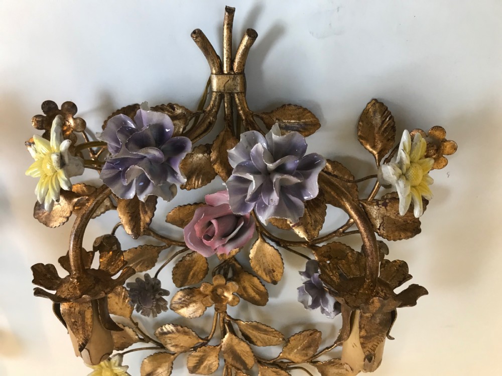 A pair of French gilt metal wall sconces shaped as botanical floral bouquets with colourful porcelain blossoms and two candle sleeves on each light fixture. View IV