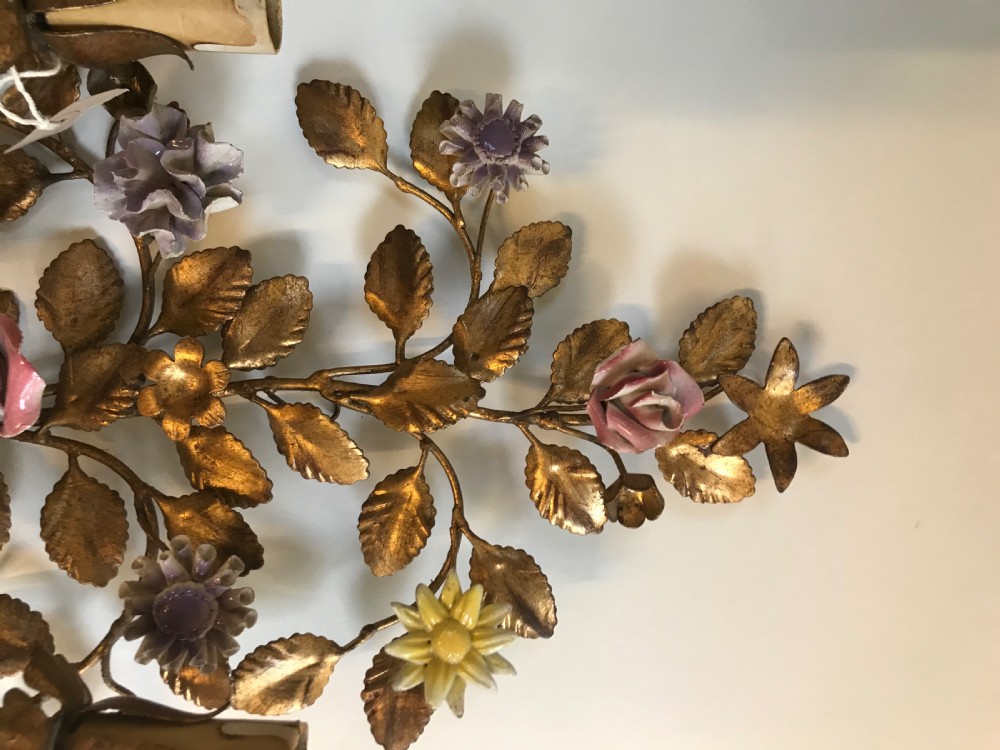 A pair of French gilt metal wall sconces shaped as botanical floral bouquets with colourful porcelain blossoms and two candle sleeves on each light fixture. View V