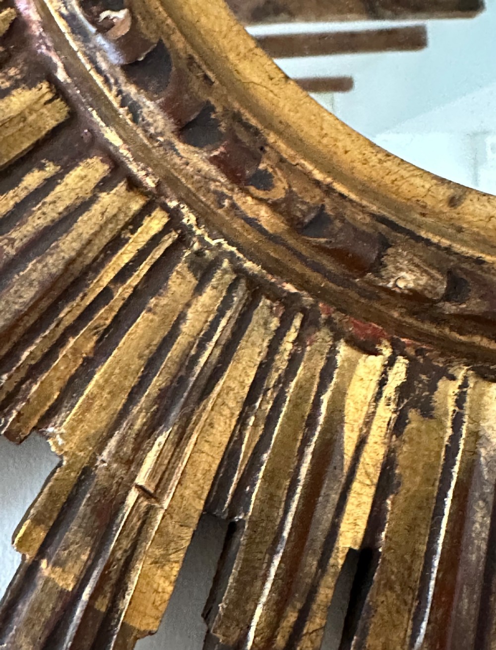A circular wall mirror set within a gilded wooden frame featuring radiating, multi-tiered sunburst rays. View VI