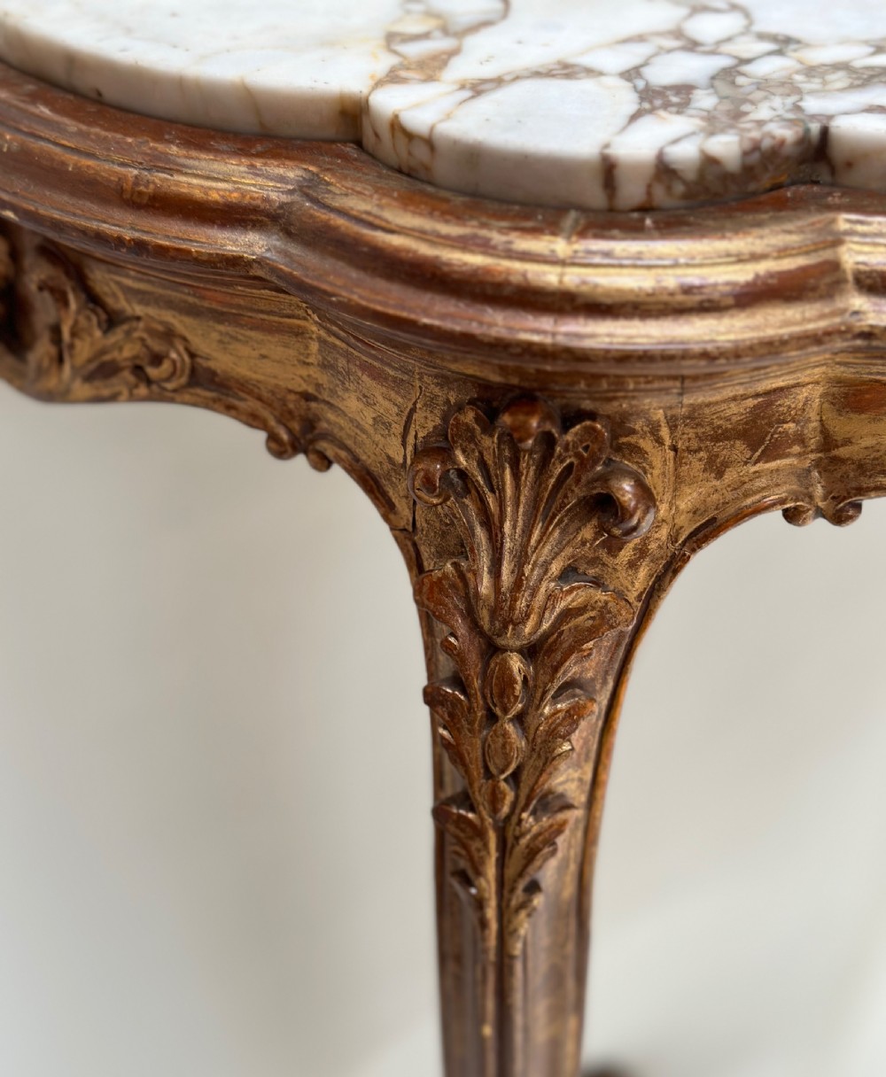 A French Rococo style demilune console table featuring a carved giltwood frame, cabriole legs with a stretcher base, and a veined marble top. View III