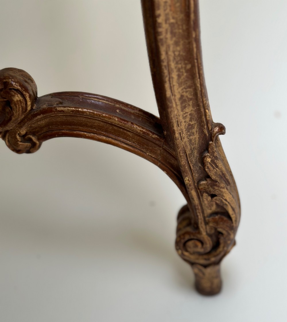 A French Rococo style demilune console table featuring a carved giltwood frame, cabriole legs with a stretcher base, and a veined marble top. View IV
