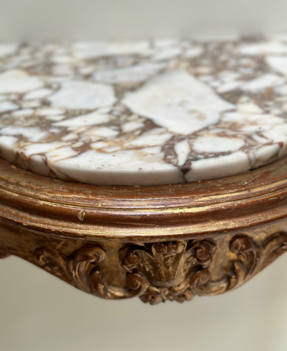 A French Rococo style demilune console table featuring a carved giltwood frame, cabriole legs with a stretcher base, and a veined marble top. View VI