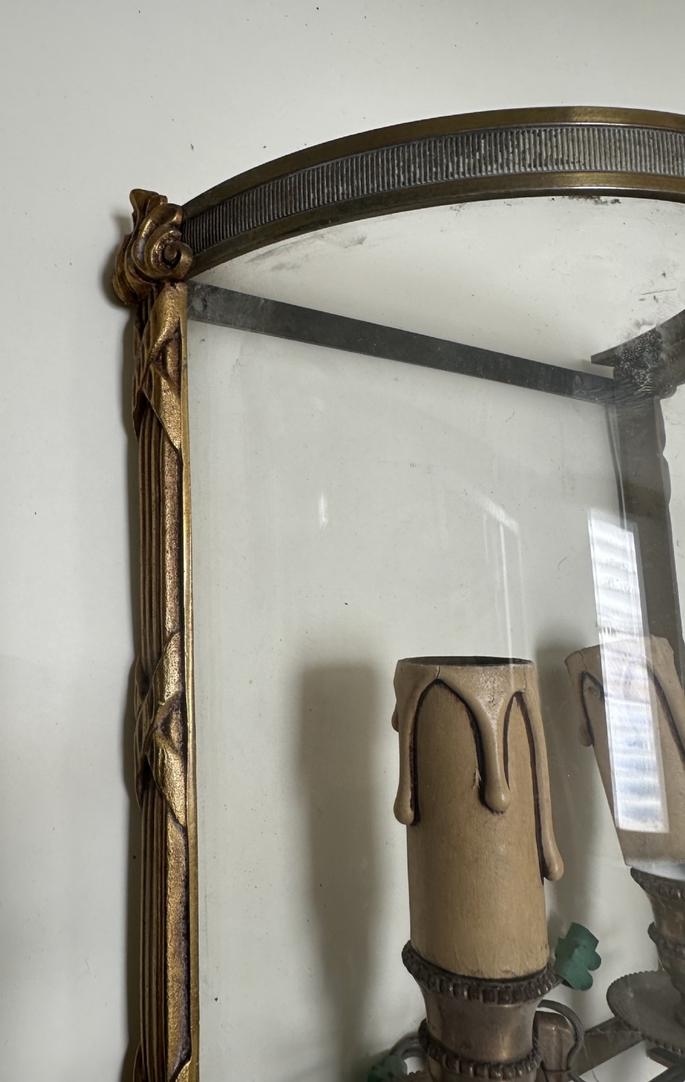 A pair of French brass wall lanterns featuring curved glass fronts, scrollwork lower supports, and twin candle sleeves within each frame. View III
