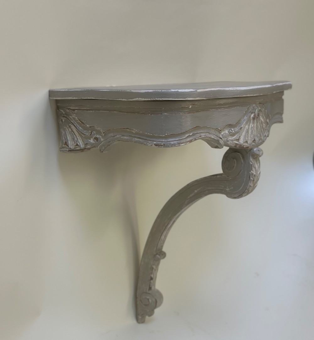 A pair of distressed grey painted French wall-mounted console tables featuring carved scallop shell motifs and single scrolled legs. View II