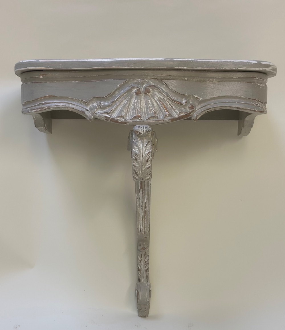 A pair of distressed grey painted French wall-mounted console tables featuring carved scallop shell motifs and single scrolled legs. View VII