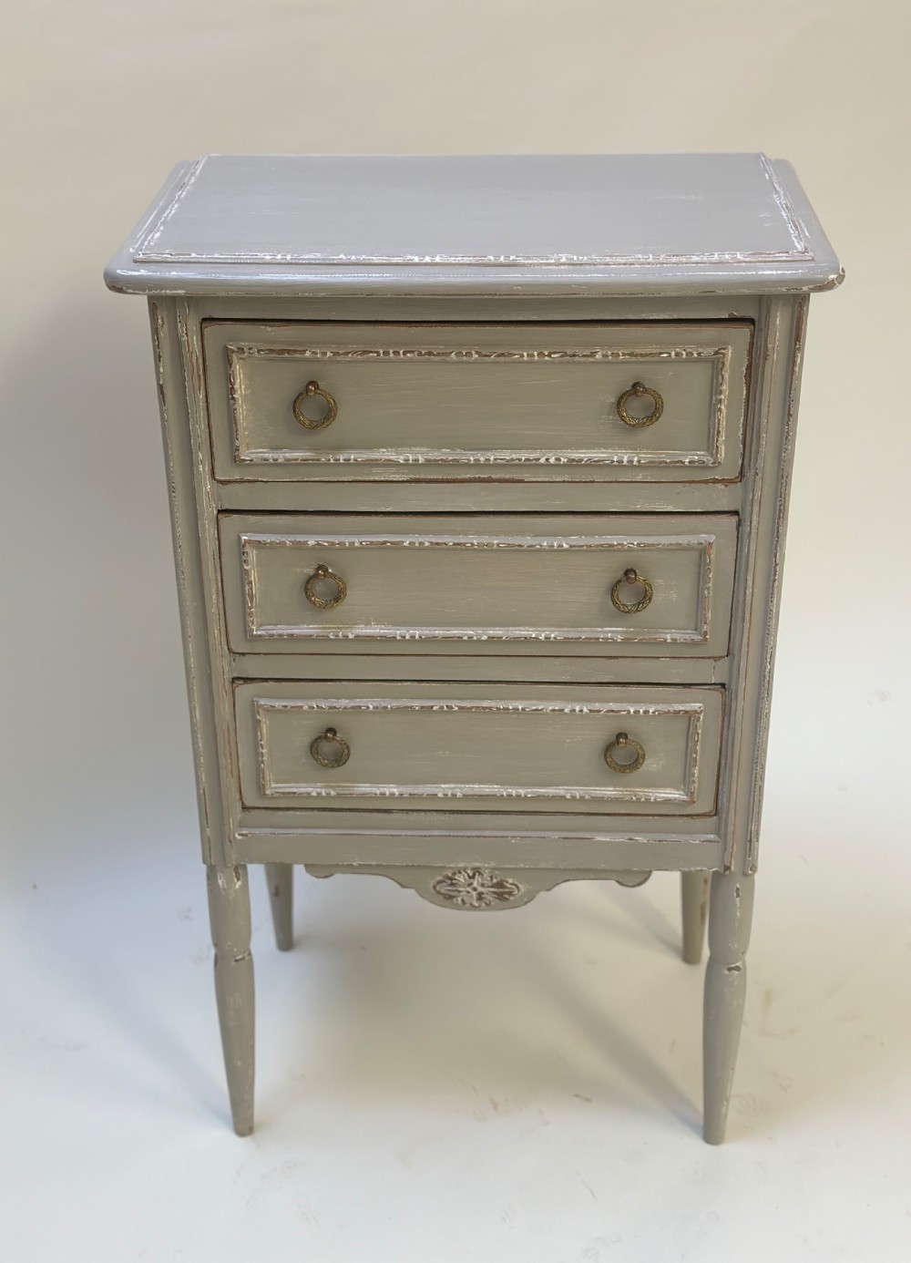 A small grey painted French-style chest with three drawers, brass ring handles, distressed edges, and tall turned legs. View II