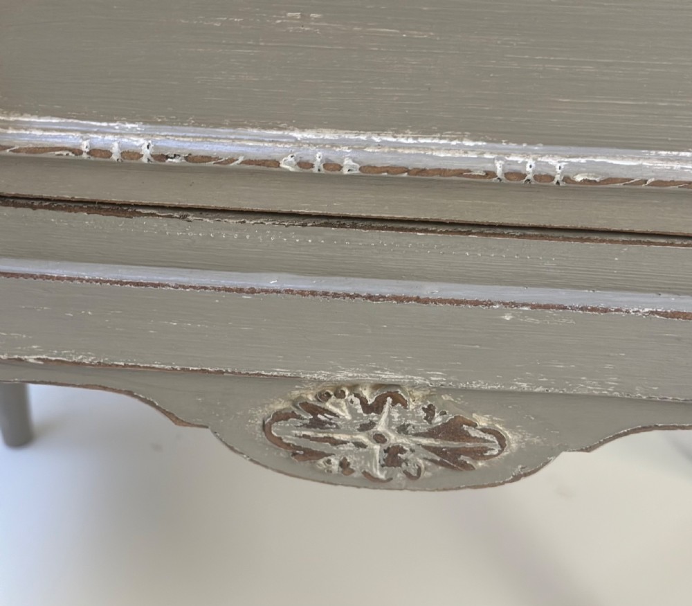 A small grey painted French-style chest with three drawers, brass ring handles, distressed edges, and tall turned legs. View III