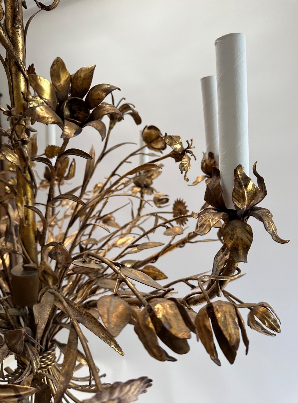 A multi-arm gilt metal chandelier featuring hand-worked botanical leaves, stems, flowers, and white tubular candle sleeves. View V