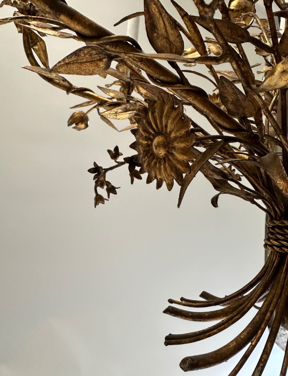 A multi-arm gilt metal chandelier featuring hand-worked botanical leaves, stems, flowers, and white tubular candle sleeves. View VI
