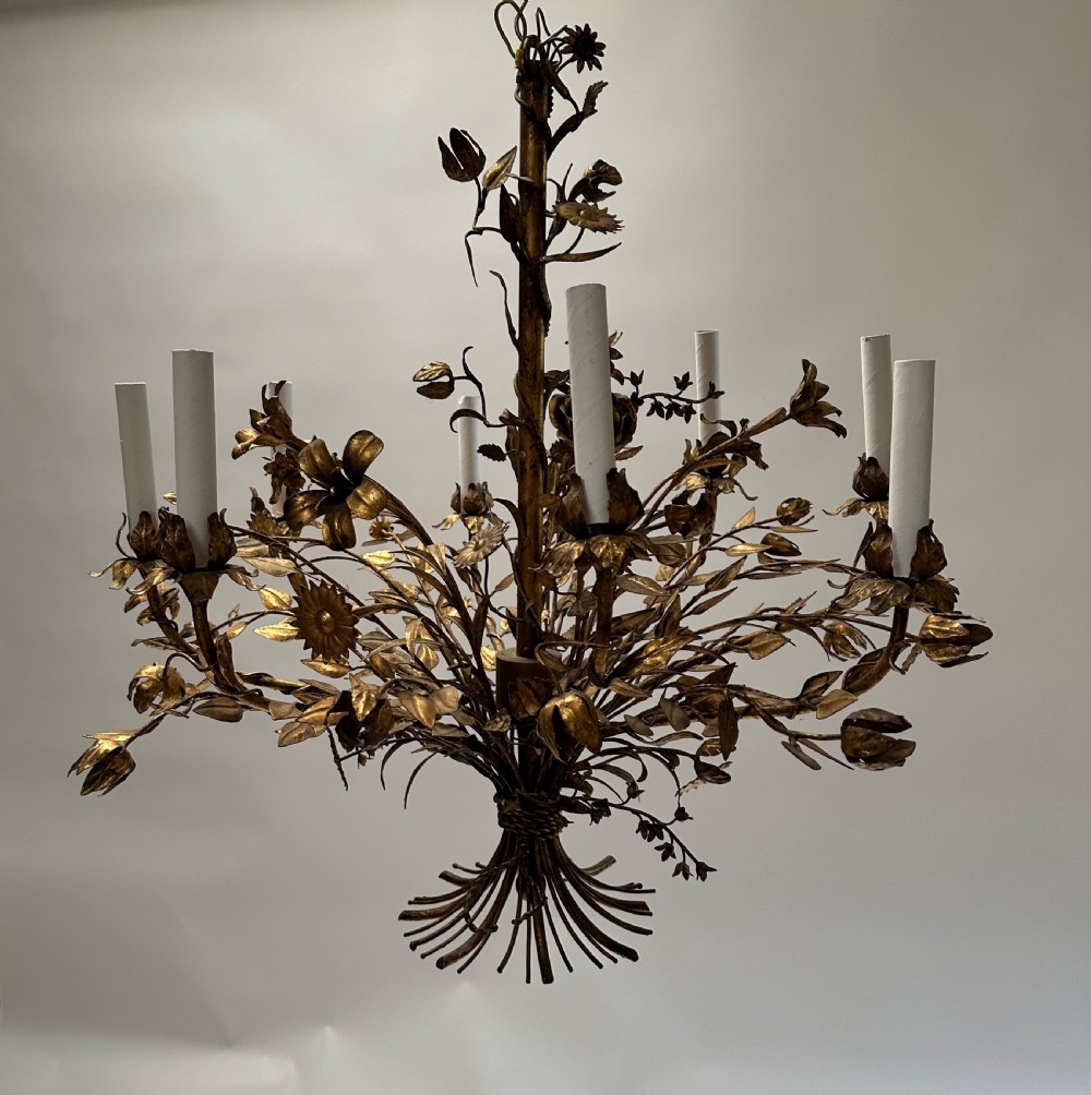 A multi-arm gilt metal chandelier featuring hand-worked botanical leaves, stems, flowers, and white tubular candle sleeves. View IX
