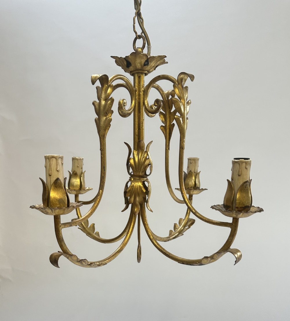 A French gilded metal chandelier featuring four curved foliate arms, leaf motifs, central leaf decorations, and candle-style bulb holders.