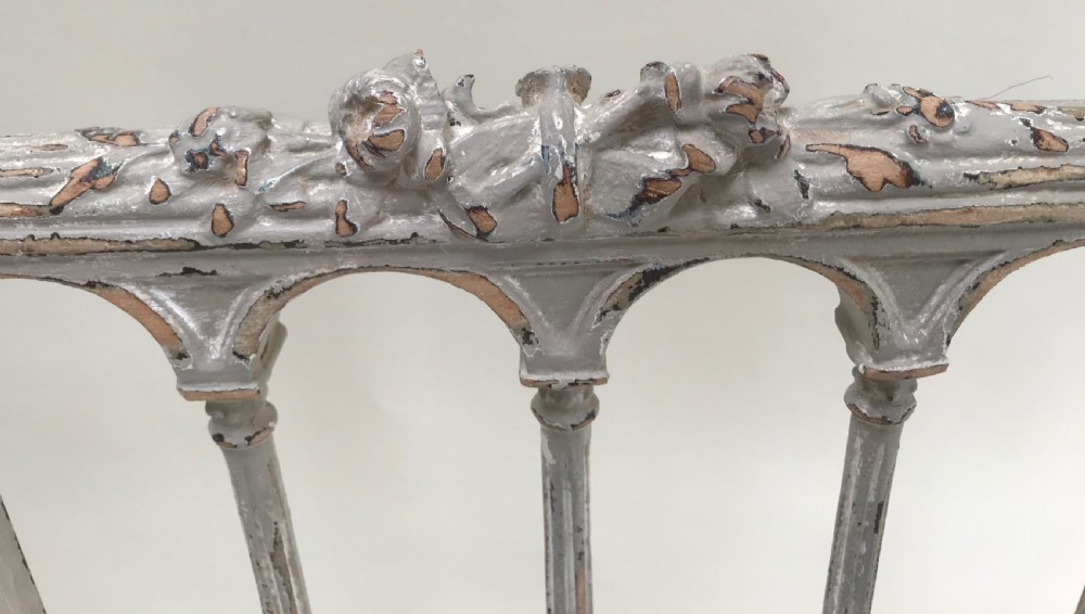 A pair of French Louis XVI style side chairs featuring distressed grey painted wooden frames, carved arcade backrests, and neutral white upholstered seats. View II
